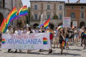 Corteo Pride in piazza con bandiere arcobaleno e striscioni “Dignità, uguaglianza, libertà” davanti a edifici storici