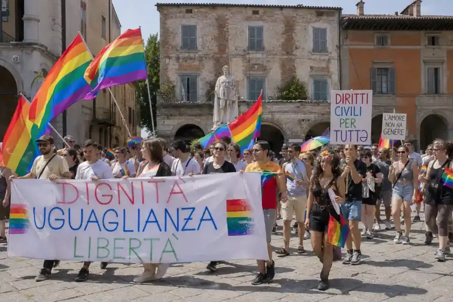 Corteo Pride in piazza con bandiere arcobaleno e striscioni “Dignità, uguaglianza, libertà” davanti a edifici storici