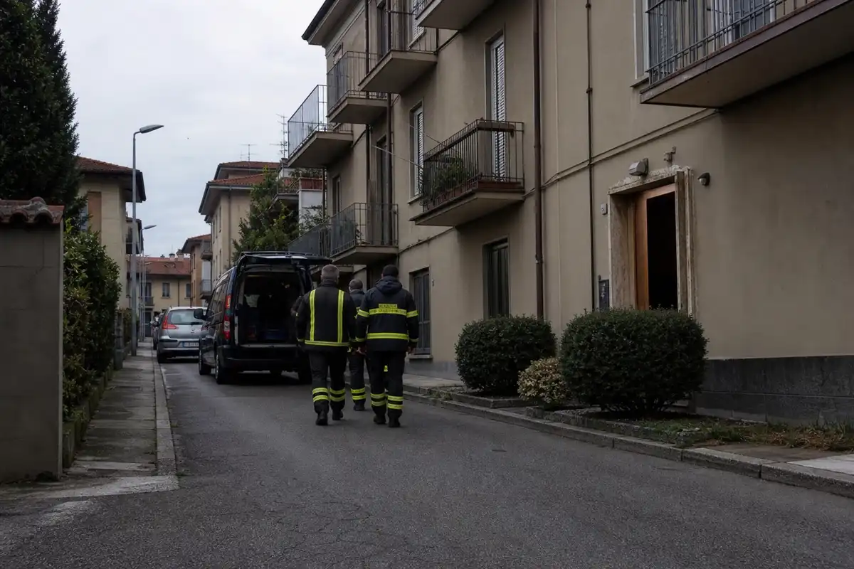 Soccorritori con giacche riflettenti in una strada residenziale, vicino a un furgone e all’ingresso di un palazzo