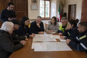 Riunione in municipio: operatori e volontari intorno a un tavolo con mappe e piani di emergenza