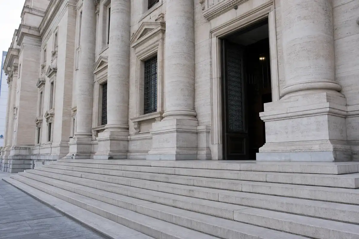 Scalinata e ingresso di un palazzo di giustizia in pietra con alte colonne e portone socchiuso