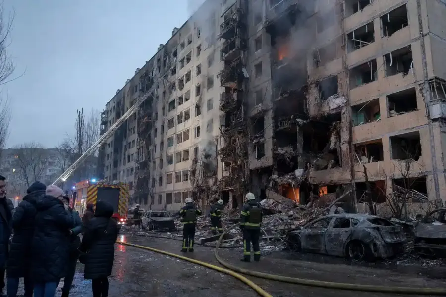 Palazzo residenziale sventrato con fumo e fiamme, vigili del fuoco e auto bruciate in strada