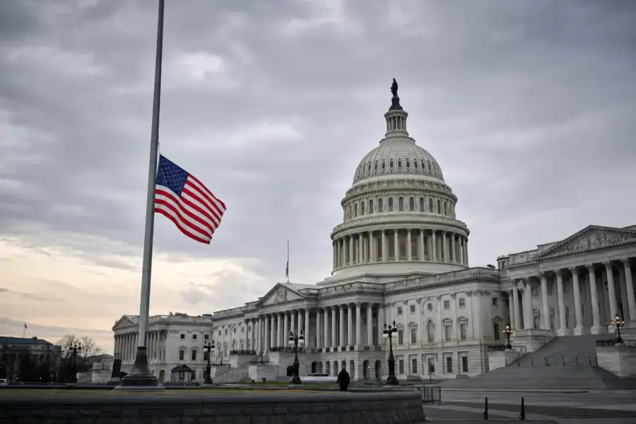 Campidoglio degli Stati Uniti con bandiera americana a mezz’asta sotto cielo nuvoloso