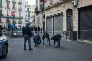 Agenti di polizia al lavoro in una piazza, area transennata con nastro e marker delle prove vicino a un ingresso metro