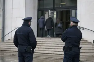 Due agenti di polizia penitenziaria di spalle davanti all’ingresso di un tribunale, con persone che entrano